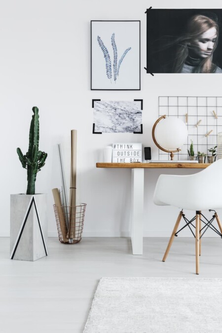 Уютные акценты создаются за счет чёрных и серых картин, мраморной подставки под кактус и глобуса с коричневой ручкой.